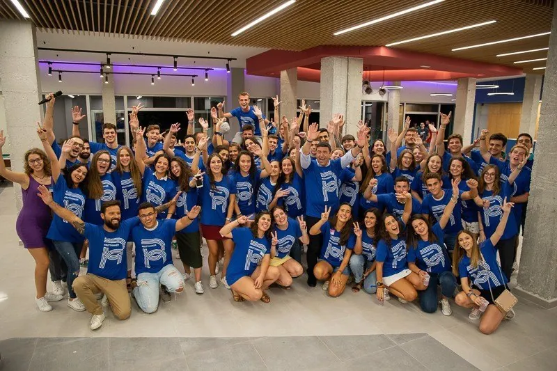 Gran grupo de residentes con la camiseta azul de la RUT celebrando en el hall